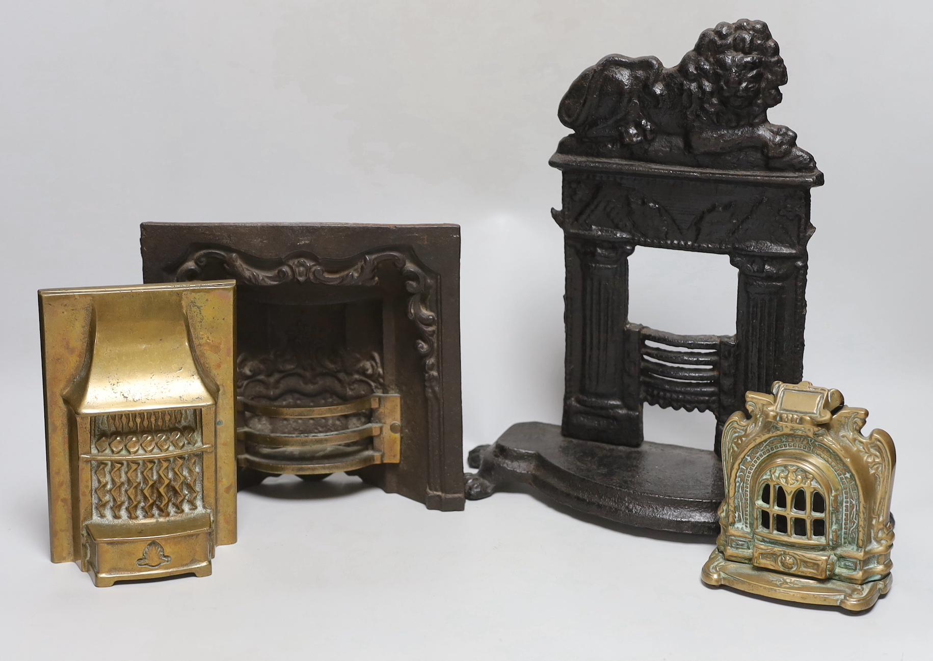 A Victorian cast iron model firegrate, a cast brass model firegrate and a similar stove, tallest 32cm